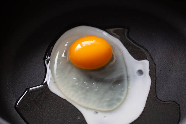 istock Cooking fried eggs, cooking in a black frying pan 2203567453