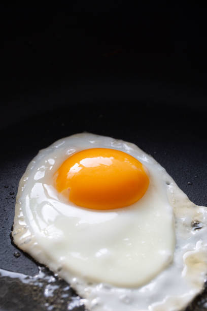istock Cooking fried eggs, cooking in a black frying pan 2203567455