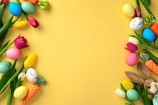 istock Happy Easter concept. Flat lay composition with colorful tulips and Easter eggs, bunny, carrots on yellow background. Easter frame, greeting card template 2203568378