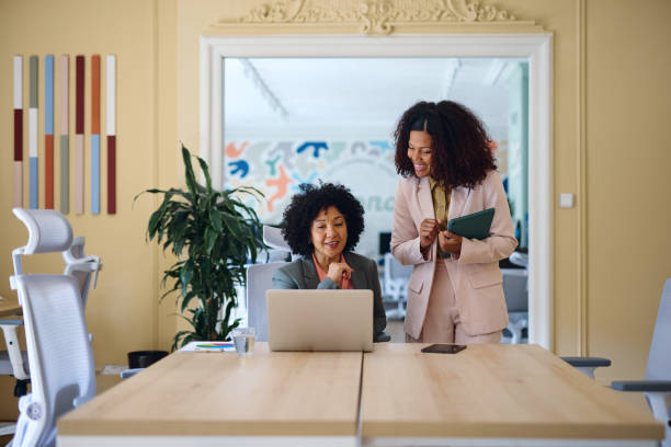 istock Two businesswomen collaborating on a project in a modern office, looking at laptop 2203569958