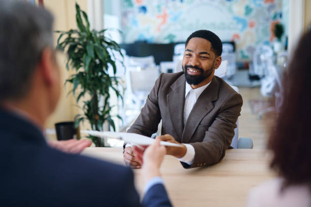istock Smiling businessman handing over documents during a meeting in a modern office 2203570548