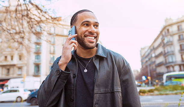 istock Smiling young man talking on smartphone in urban setting 2203573845