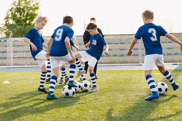 istock Young boys playing soccer training game. Junior football practice competition between players running in a duel and kicking a soccer ball. Training and football match between youth soccer teams 2203576937
