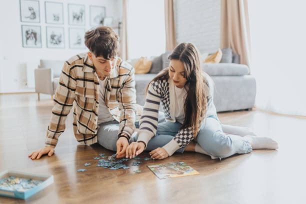 istock Young couple having fun while doing jigsaw puzzle together at home 2203581418