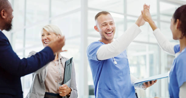 istock Doctors, high five and celebration with team at clinic for breakthrough, progress and medical solution. People, men and women with cheers, success and goals for healthcare innovation at hospital 2203581725