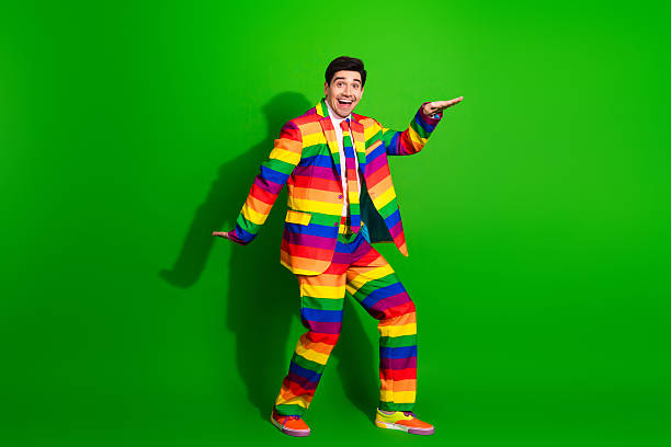 istock Young Man in a Rainbow Striped Suit Posing Joyfully Against a Green Background 2203583234