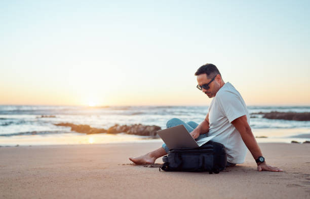 istock Freelancer working on laptop at beach during sunset 2203583626