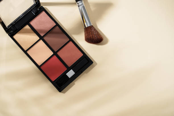 istock Make up palette and cosmetic brushes at pastel background with hard shadows. 2203587321