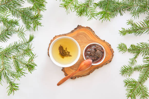 istock Herbal tea and pine cone jam on wooden board with fir branches 2203589128