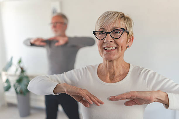 istock A happy senior couple exercises together at home, practicing light aerobic movements in a bright living space, promoting health, wellness, and an active lifestyle 2203589260