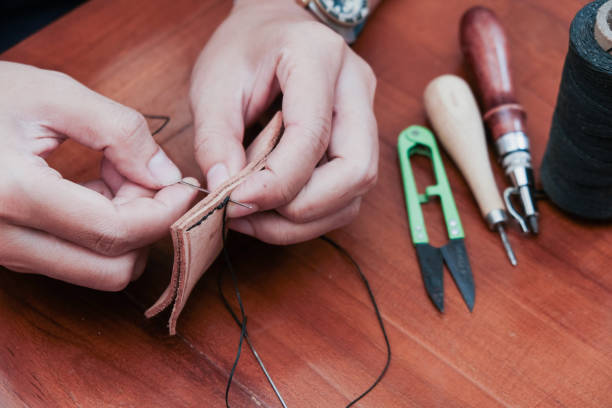 istock A closeup man hand with threads and needle , making leather goods with handstitched process in wooden table 2203589896