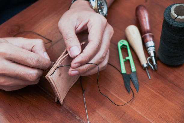 istock A closeup man hand with threads and needle , making leather goods with handstitched process in wooden table 2203589989