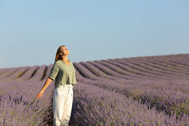 Casual woman is breathing fresh air standing in lavender field stock photo
