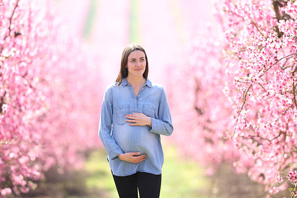 istock Pregnant woman walking through a flowered field 2203592176