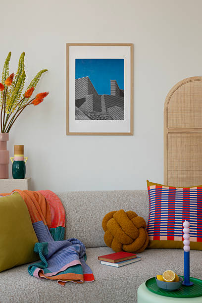 istock Modern living area with a light beige couch, accented by colorful geometric pillows, a soft throw, and unique decor elements. 2203596289