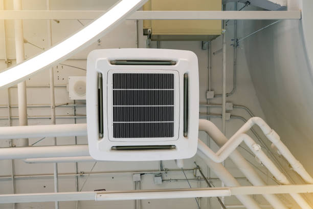 istock A ceiling-mounted air conditioning unit is showcased in a bright industrial setting. Pipes and ventilation systems are visible around the unit, emphasizing its cooling function 2203598911