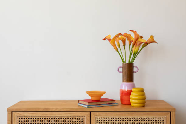 istock Bright and colorful home decor setup featuring a wooden vase with gerbera daisies, a bold red glass centerpiece, and unique candles, adding a playful touch to a modern interior. 2203599607