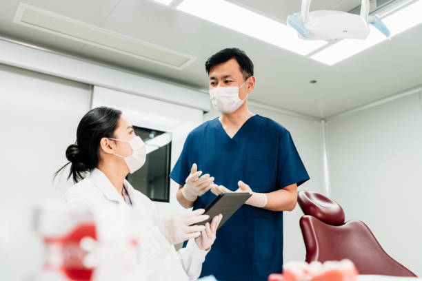 istock Two Asian dentists discussing the operation plan on digital tablet at the dental office. 2203601628