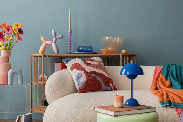 istock Modern decorative setup with vibrant flowers, a balloon dog sculpture, white sofa and design blue lamp. Stylish home decor. 2203602181
