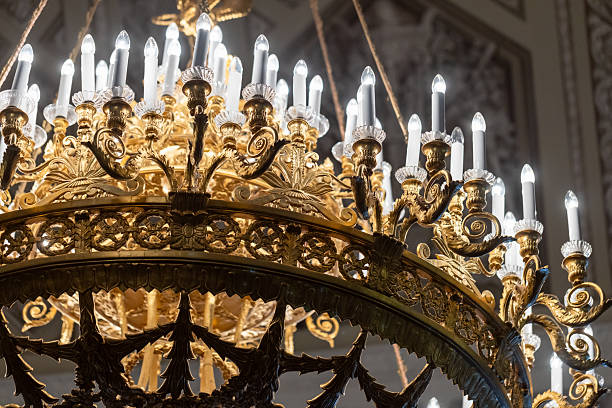 Golden chandelier adorned with intricate designs and multiple faux candle bulbs, emphasizing luxury and sophistication. Ideal for capturing grandiose atmospheres, aesthetic charm