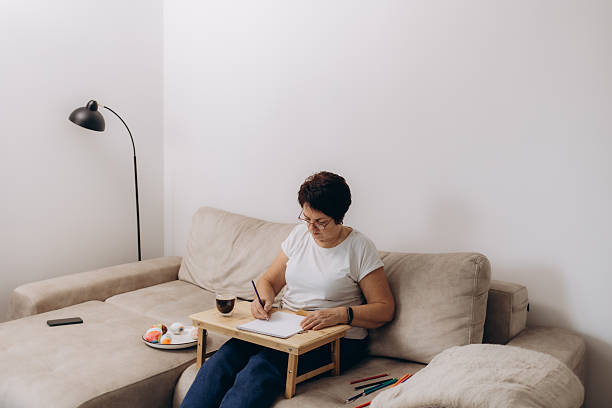 istock Woman Sitting on a Couch Sketching on Paper Using Color Pencils 2203605278