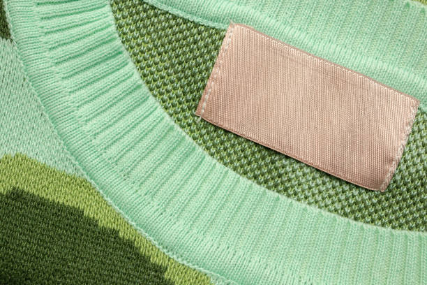 istock Brown blank laundry care clothes label on green shirt fabric background 2203605544
