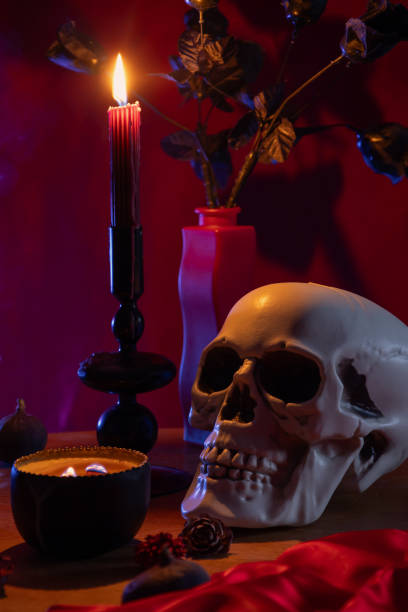 istock scull and burning candles on dark red background 2203608848