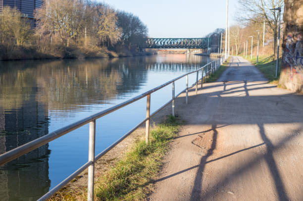istock Towpath along canal with metal railing and bridge in background 2203610461