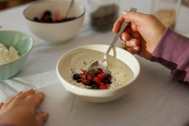 Woman making healthy kefir drink porridge with chia seeds, oatmeal and berries Detail of female hand mixing berries into healthy homemade kefir drink porridge with oatmeal and chia seeds - healthy nutrition concept eating chia seeds stock pictures, royalty-free photos & images