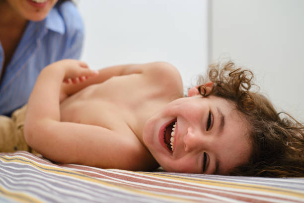 Smiling little girl lying on green grass outdoors, top view