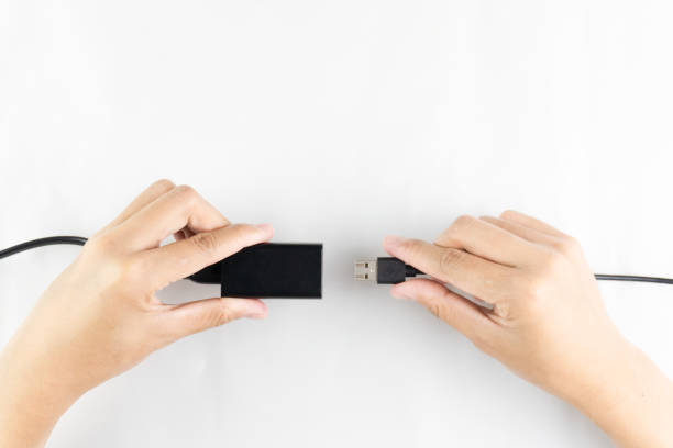 istock A pair of hands are shown connecting a black USB cable to a power adapter against a white surface backdrop 2203615112