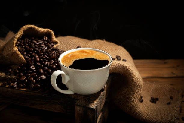 istock Coffee cups with roasted coffee beans arranged on table, top view. with a black background and dark colors 2203617250