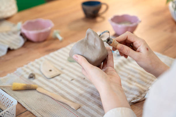 Close up of little boy painting his unique clay cup. Children's workshop at pottery studio. Creating ceramics with own hands. Selective focus.