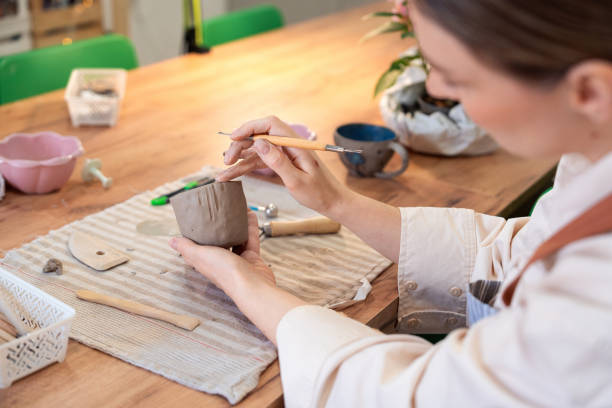 istock Woman carving handmade clay mug at pottery studio 2203618676