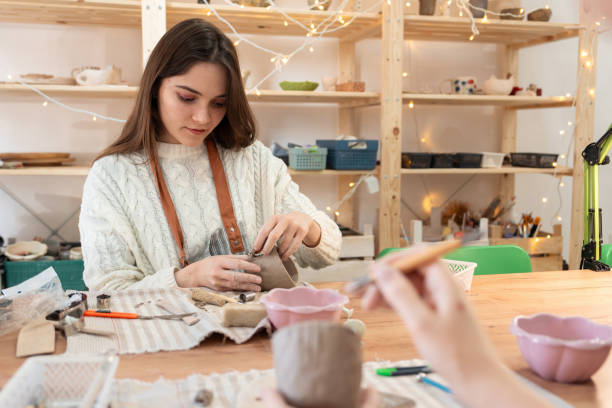 istock Young woman concentrated on making handmade mug at pottery class 2203618695