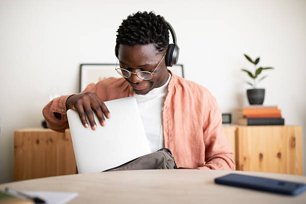 istock Young man putting laptop in bag after finishing work 2203623392