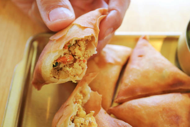 istock Hand Picking Delectable Samosa Filled with Spiced Chicken and Veggie 2203624103