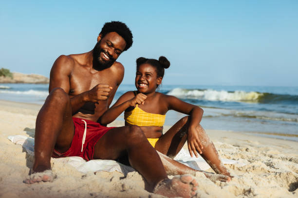 istock Father and daughter playing in the sand on a sunny beach 2203625423