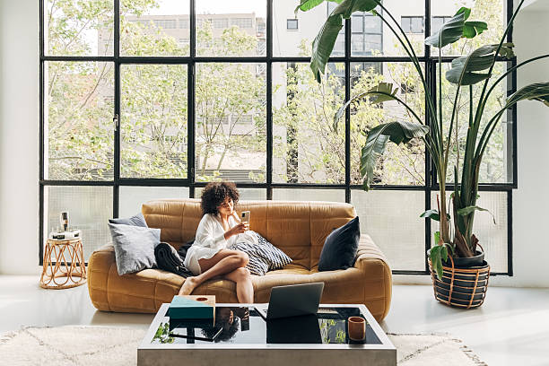 istock Young woman relaxing on sofa using smartphone in modern apartment 2203626091