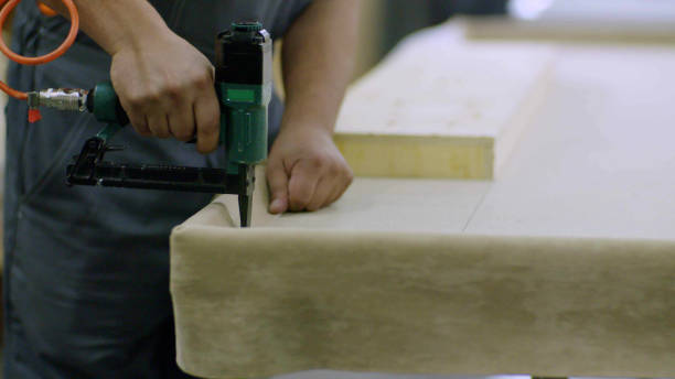 Close up on hands of furniture maker using mattress sewing machine at manufacturing plant
