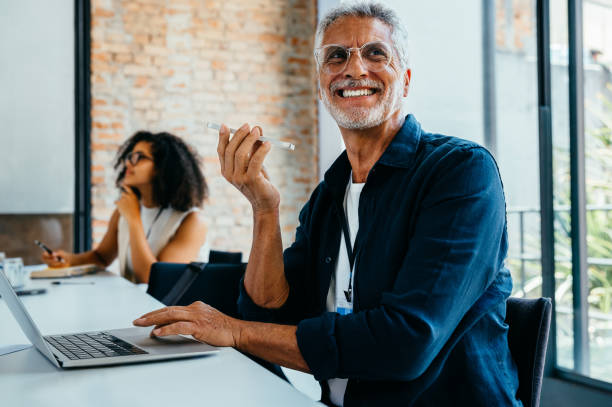 istock Joyful senior man in a modern office setting enjoying a productive meeting with diverse colleagues around a conference table 2203626888