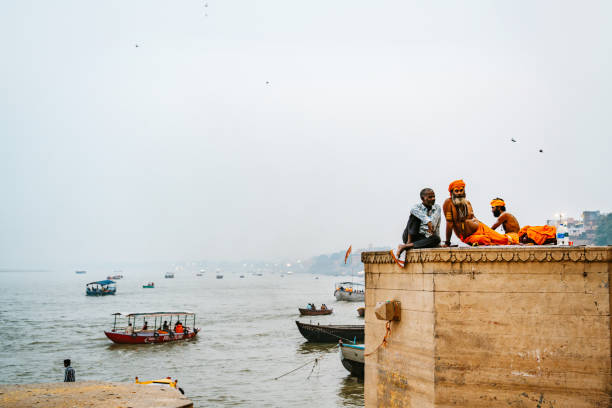 People wearing traditional attire by the Ganges River in Varanasi, a cultural and spiritual hub.