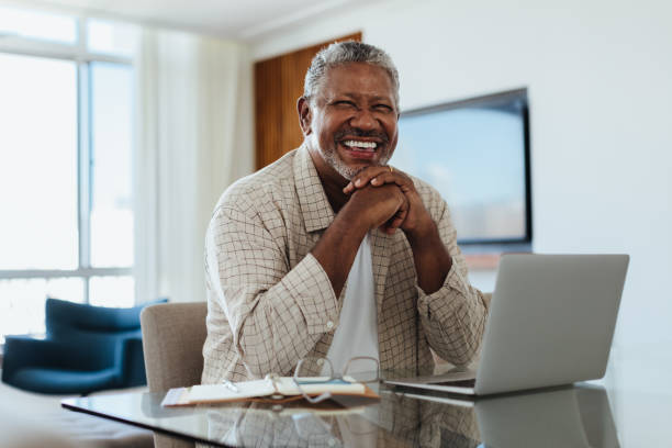 istock Cheerful senior man working on laptop at home office with bright smile 2203627083