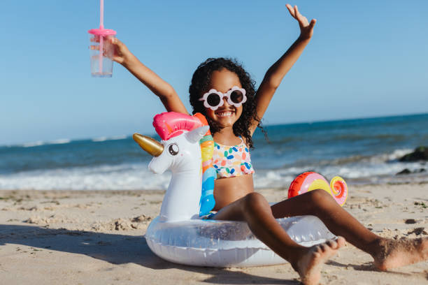 istock Happy girl having fun at the beach with a unicorn floaty 2203628678