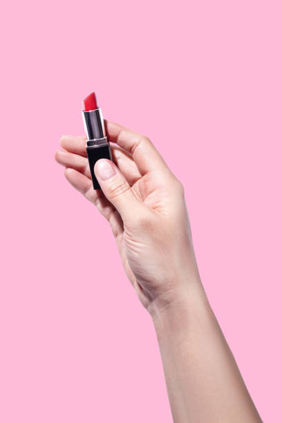 istock A woman's hand holds red lipstick isolated on pink background vertical 2203629574