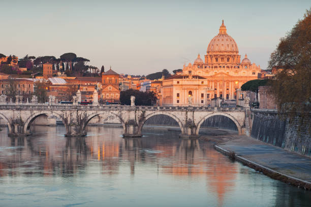 The Tiber River with Ponte Sant'Angelo and St. Peter's Basilica in the distance at sunrise.