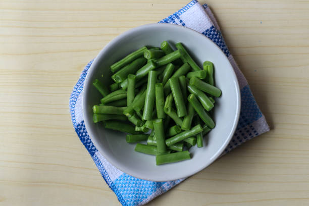 Fresh green beans on a plate, on a wooden table