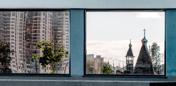 Reflection of domes and tree on glass window, contrasting with urban architecture. Modern multi-story building in downtown, residential condo with concrete facade. Spirituality, religion, cityscape,