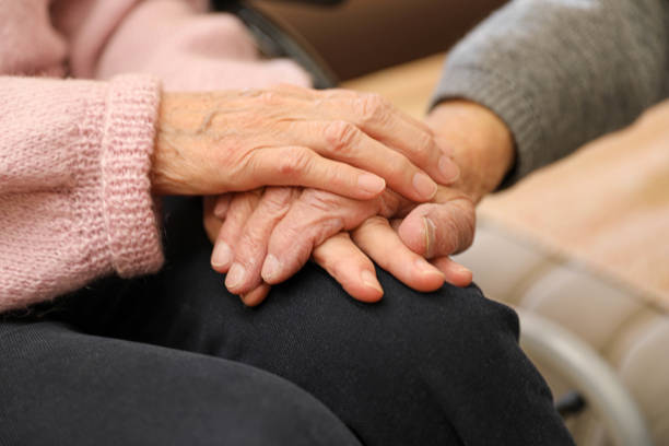 istock Senior woman and caregiver holding hands in support. 2203636603