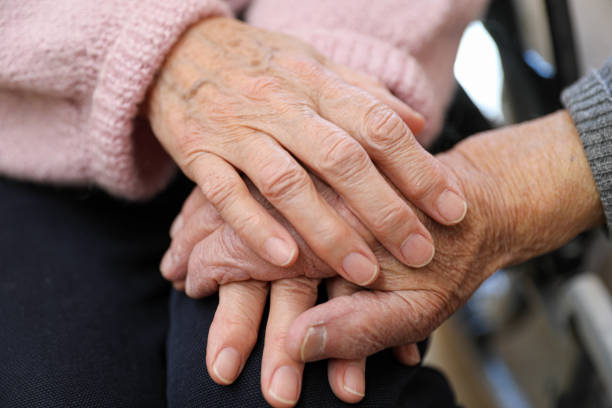 Compassionate Care: A Caregiver Holding an Elderly Woman’s Hands